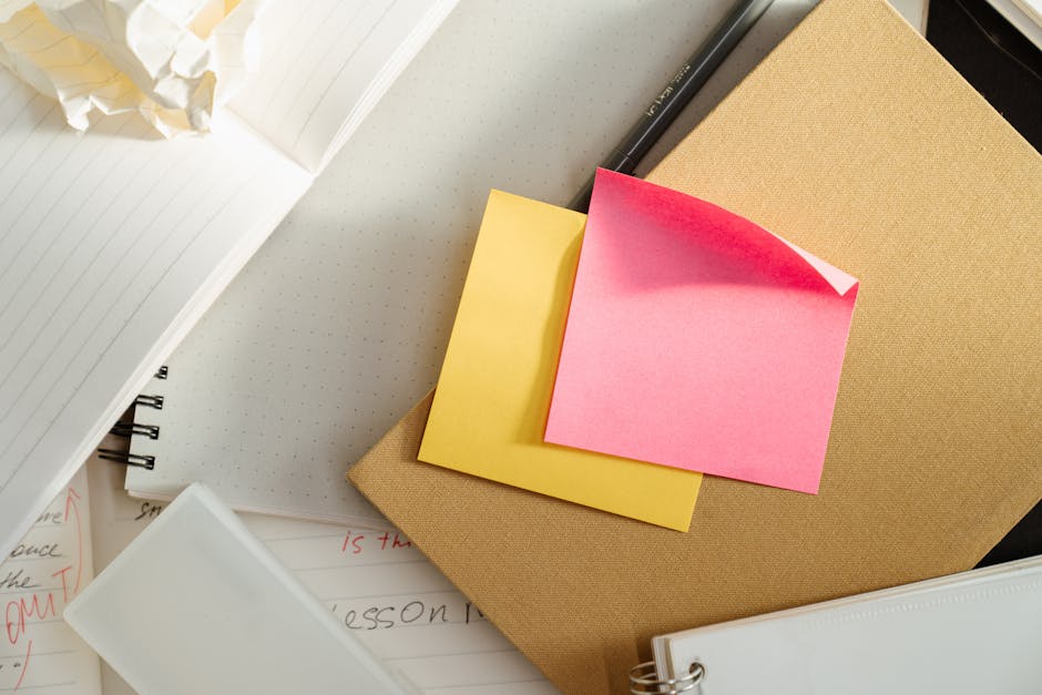 A flat lay of office supplies with notebooks, sticky notes, crumpled paper, and a pen.